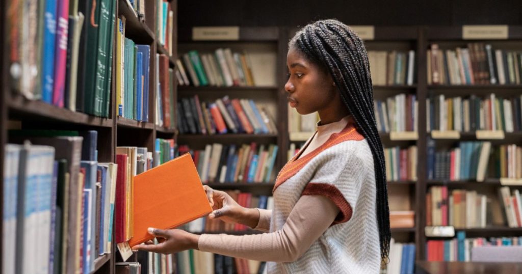 foto de mulher pegando um livro na biblioteca.